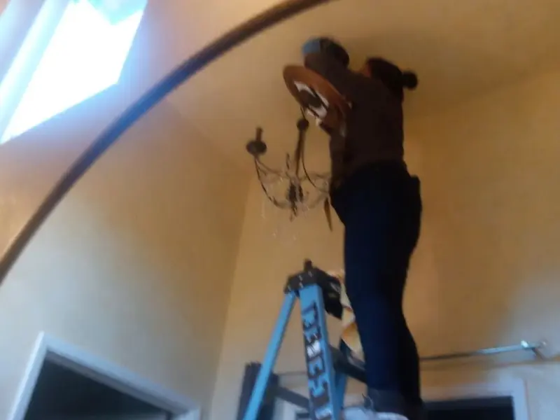 Electrician installing a chandelier in a Upton residence